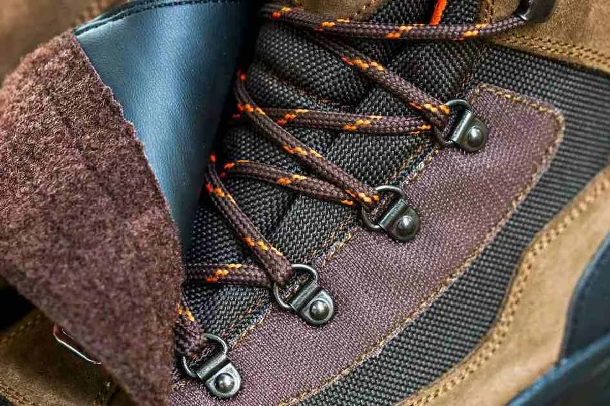 Hiker adjusting laces on hiking boots for comfort and support.