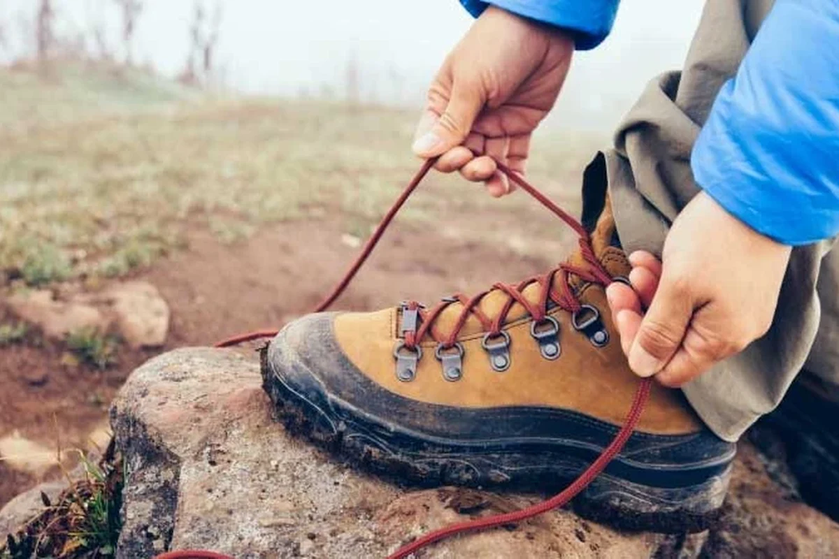 Hiker adjusting laces on hiking boots for comfort and support.