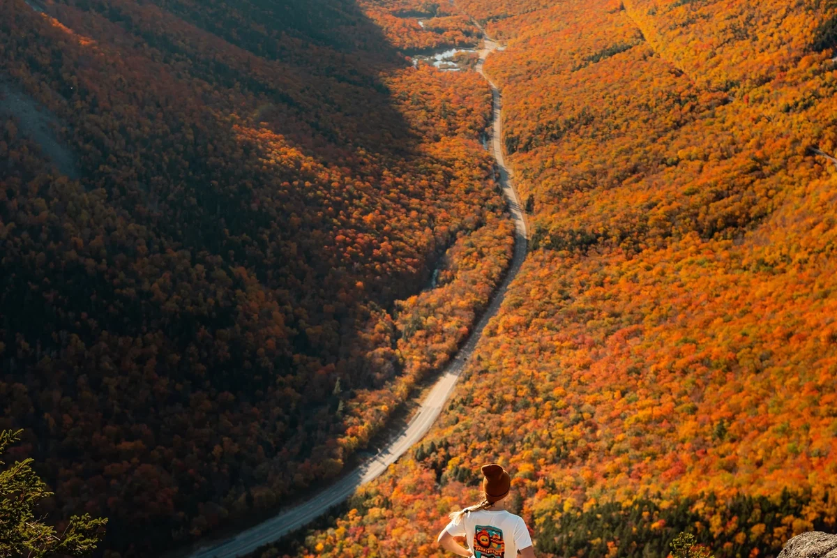 Hiker enjoying the stunning views on a trail in New Hampshire's White Mountains.