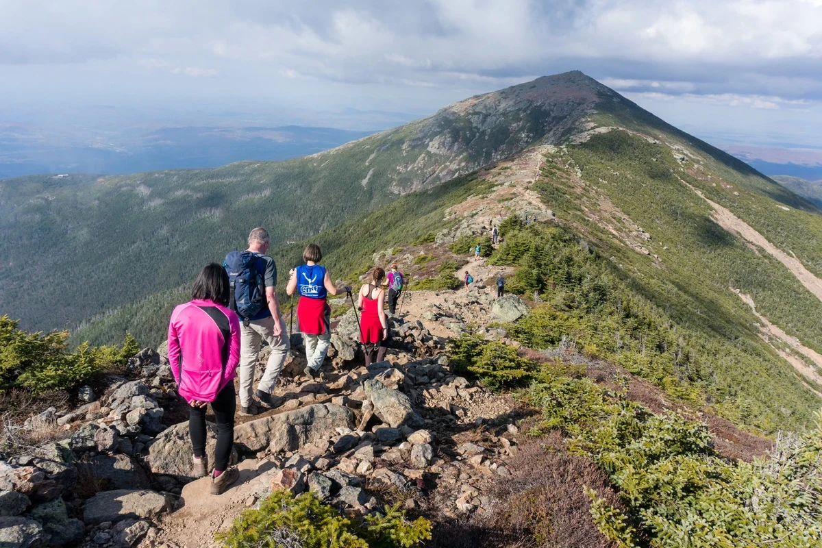 Hiker on a trail in the NH White Mountains with stunning views